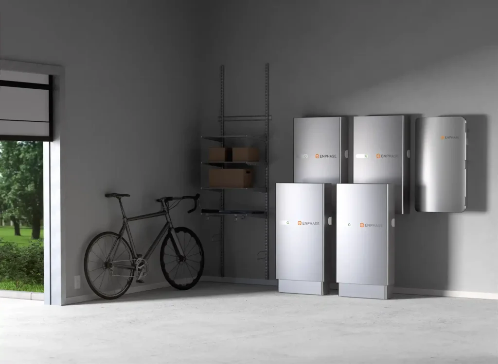 A garage interior with three large silver ENPHASE battery storage units mounted on the wall.