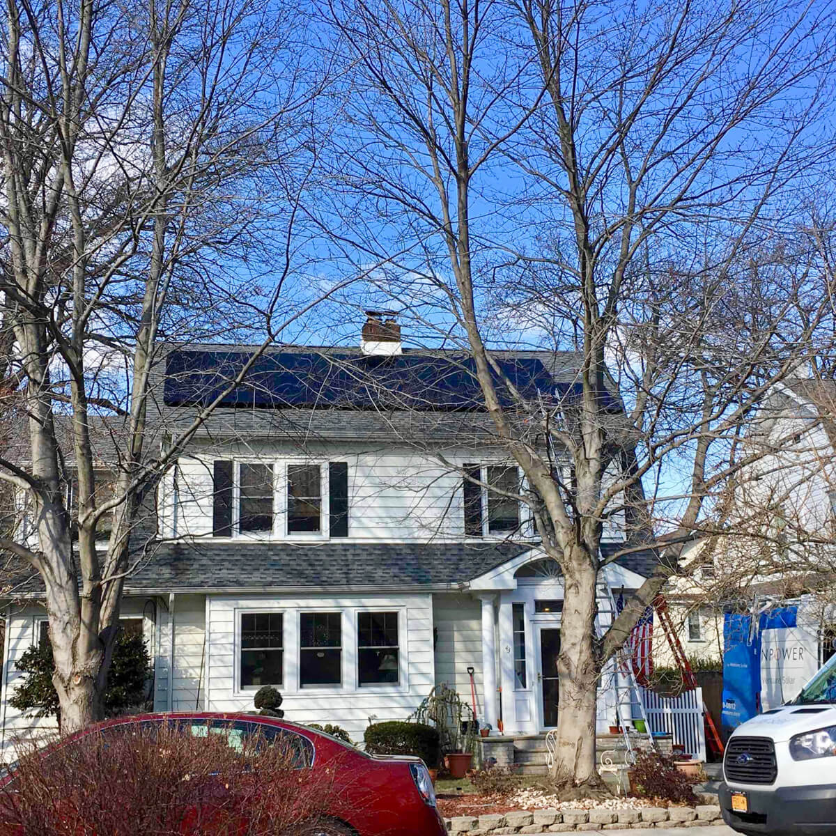 A cozy home surrounded by trees, featuring solar panels installed on the roof, capturing sunlight for clean energy.